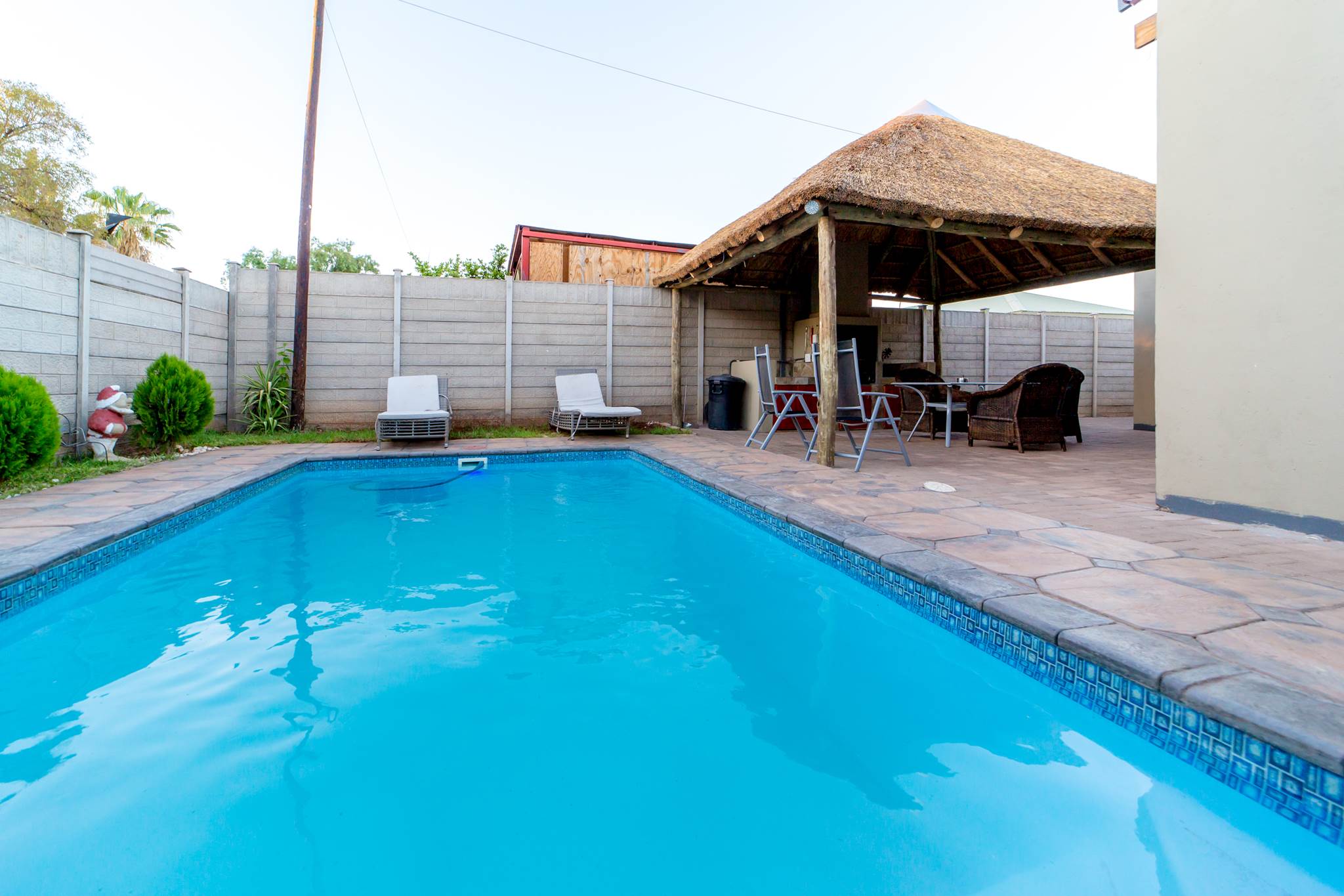 The pool and thatched lapa at Cozy Guesthouse in late afternoon light